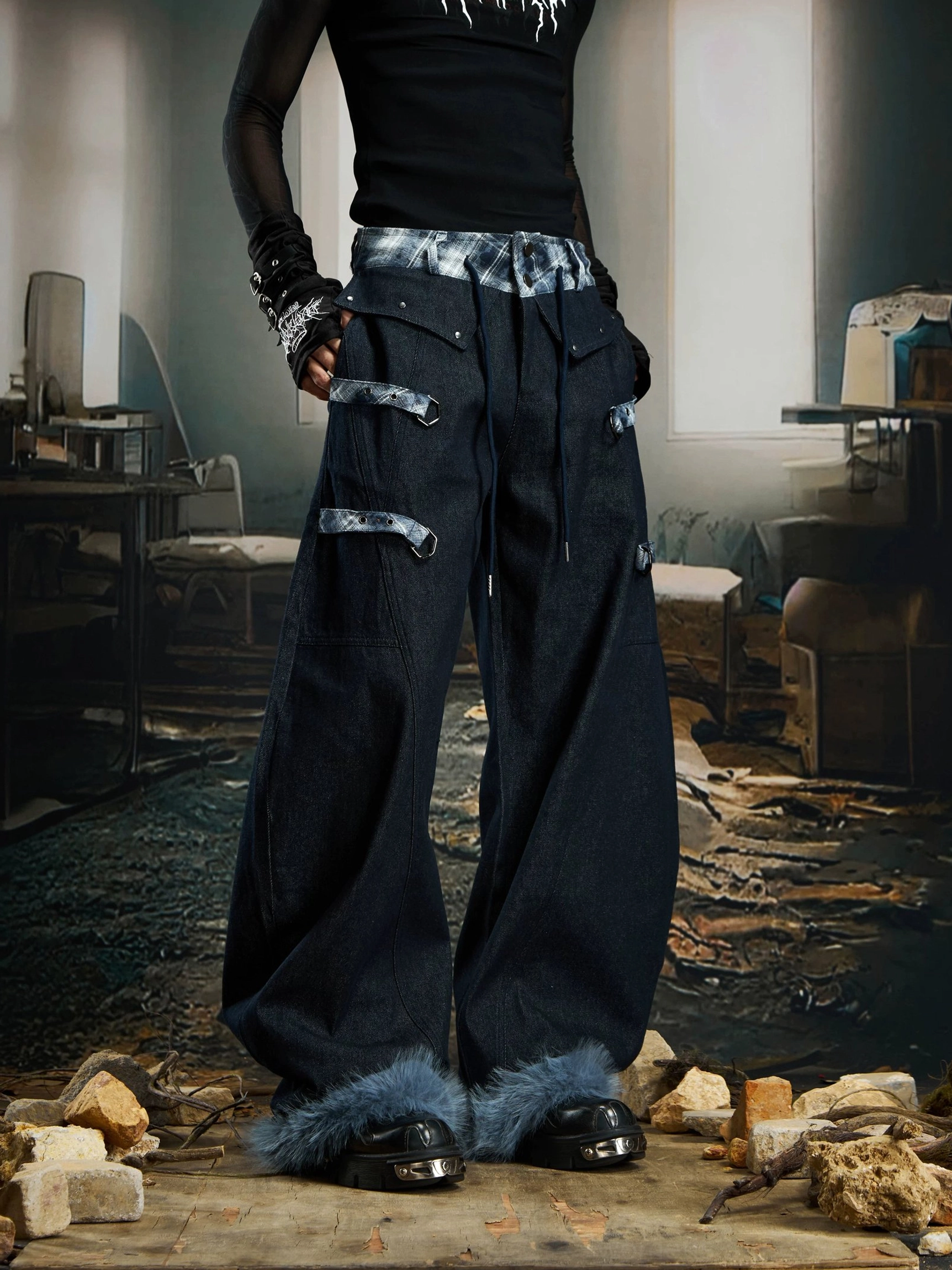 Front low-angle view of oversized black denim streetwear cargo pants with plaid waistband decorative straps and light blue faux-fur hems