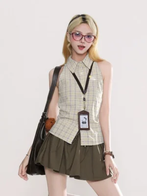 Korean-inspired preppy streetwear look with a plaid sleeveless shirt, brown pleated skirt, black leather underarm bag, and work badge accessory