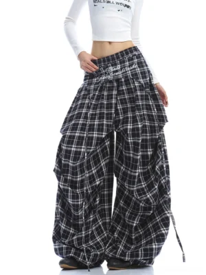 Front angled view of oversized black and white plaid cargo pants with elastic waist, drawstring details, embroidered letter accent, and large pleated pockets