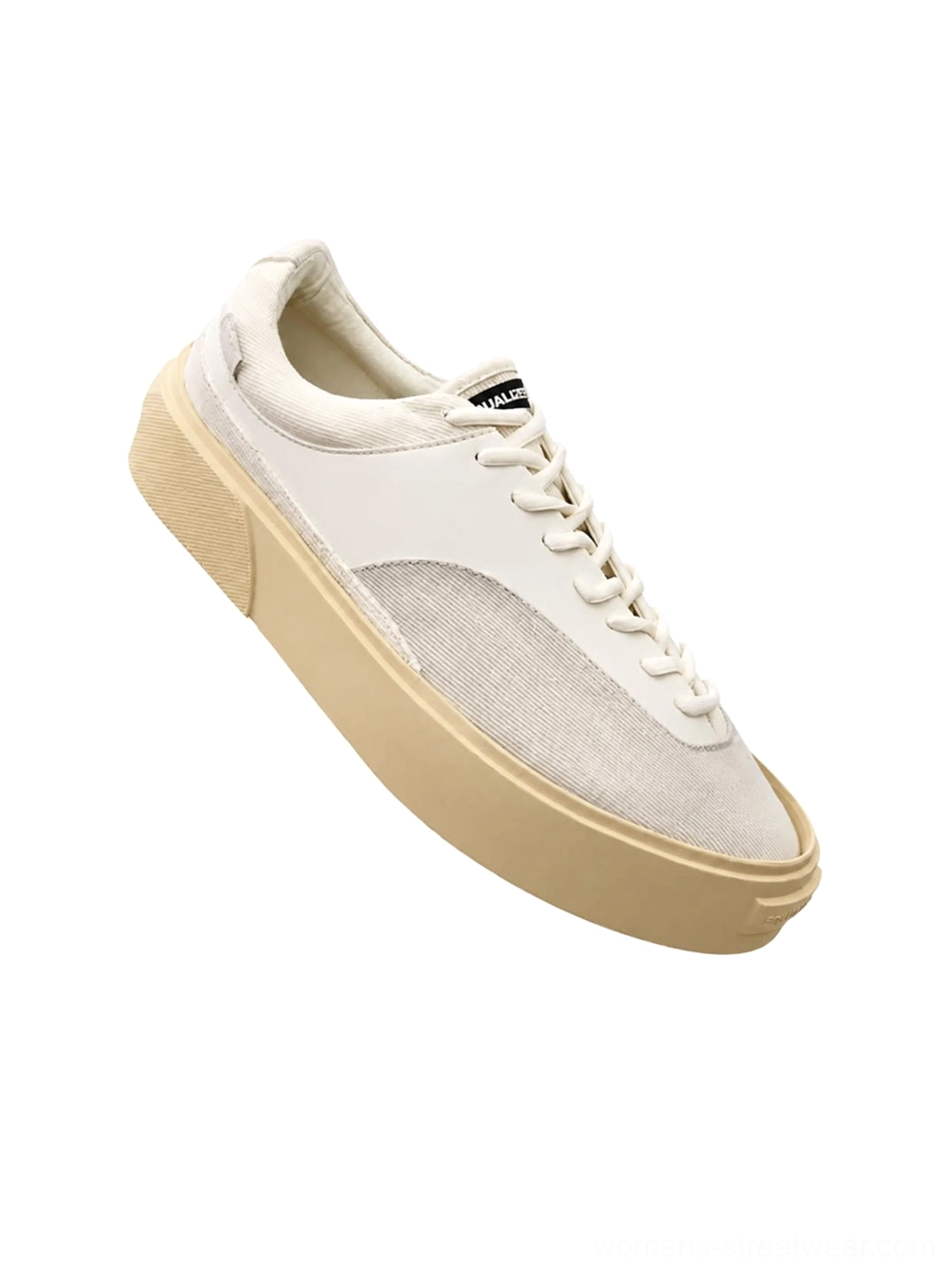 Oblique close-up of a neutral platform canvas sneaker showing the suede-style toe panel, branded tongue label, tonal laces, and substantial rubber platform sole