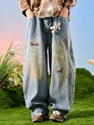 Front full-body view of light blue washed wide leg doodle jeans with sausage dog graphics handwritten text star motifs and detachable plush pendant