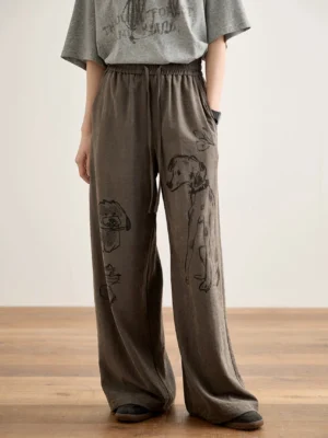 Dark brown dog print wide-leg streetwear lounge pants with relaxed fit and elastic waistband styled with a gray graphic tee