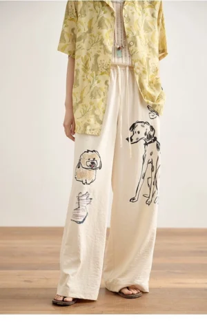 Ivory cream dog print wide-leg lounge pants with elastic drawstring waist styled with a yellow floral shirt in an indoor studio