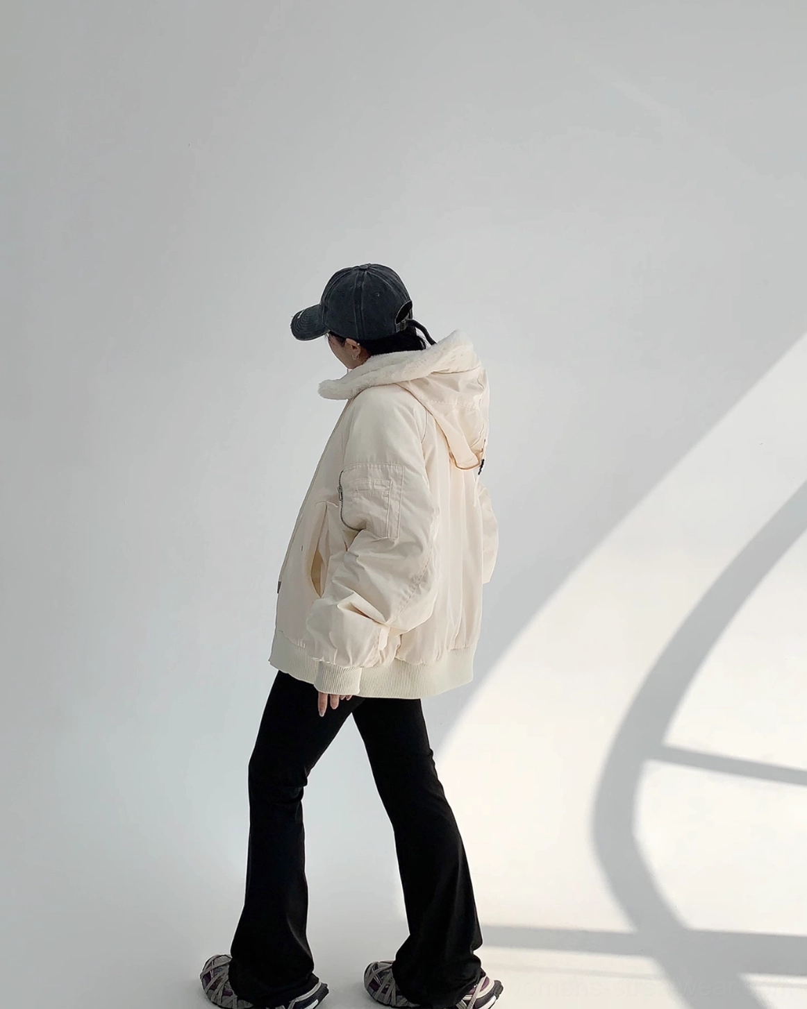Plush off-white sherpa bomber jacket with large hood, relaxed silhouette, ribbed hem, and casual urban styling