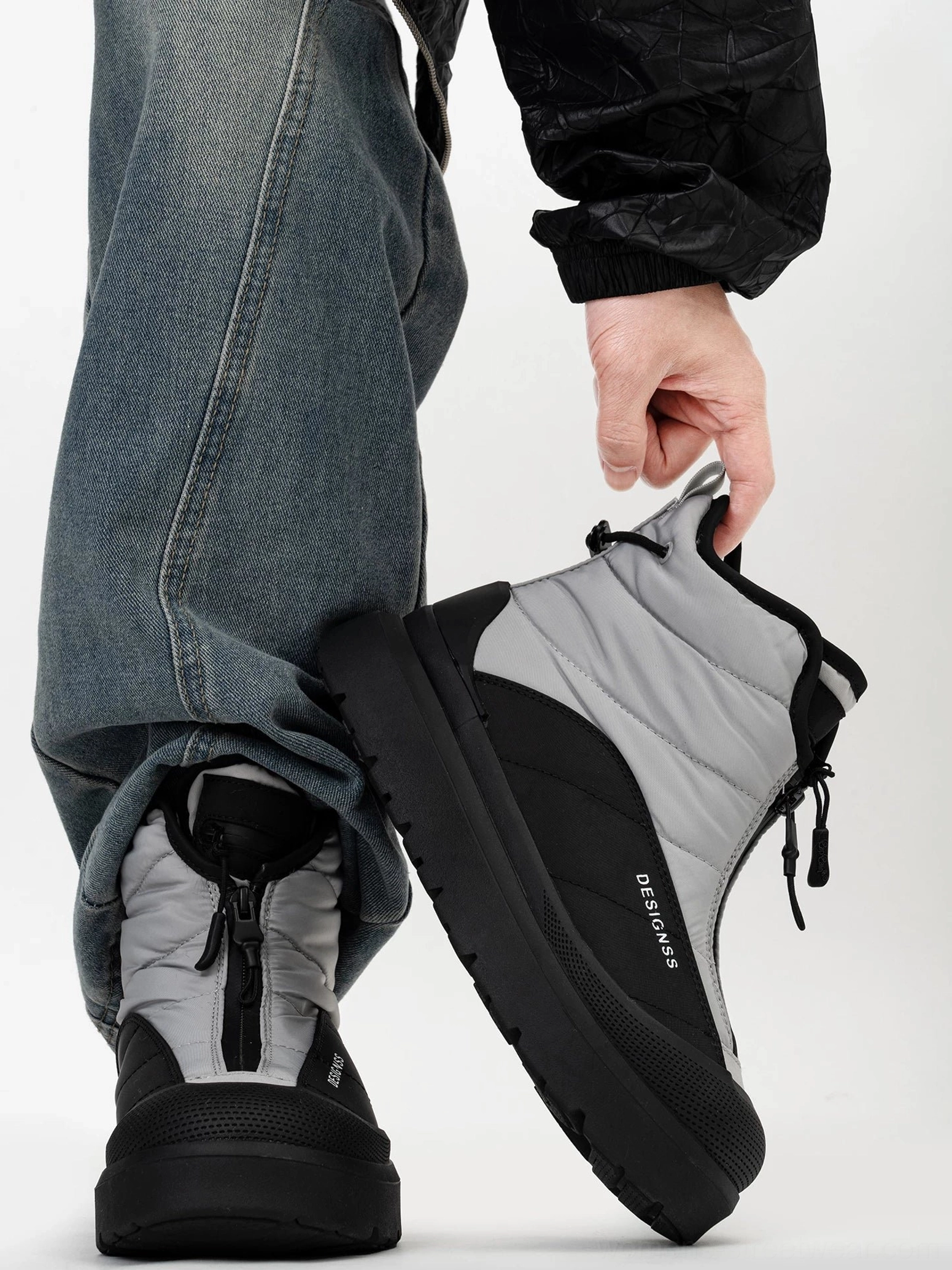 Side view of Polar Flux two-tone winter boots showing the quilted gray panels, black rubber toe cap, adjustable ankle toggle, and rugged sole
