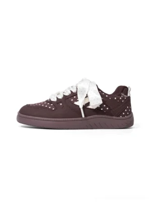Brown polka dot ribbon low top skate sneakers with contrast panels and thick flat outsole on a white background