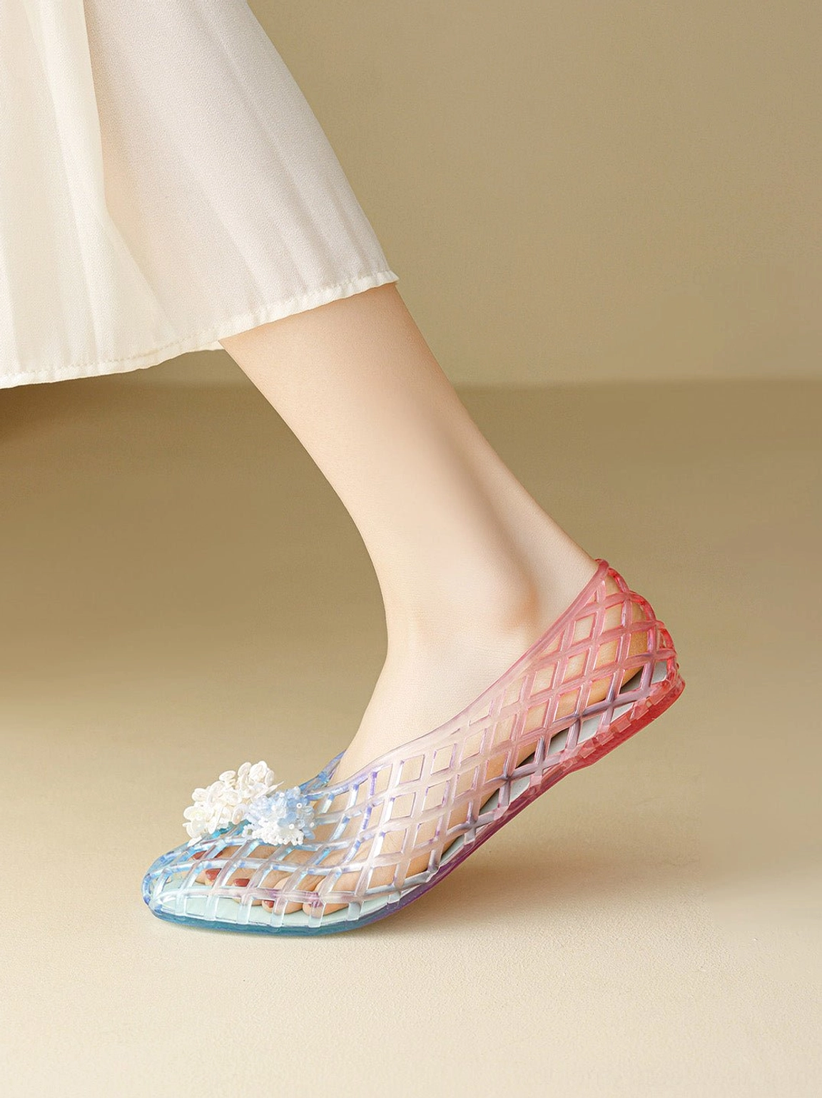 Low angle view of purple gradient jelly ballet flat with transparent sole open lattice texture and flower ornament