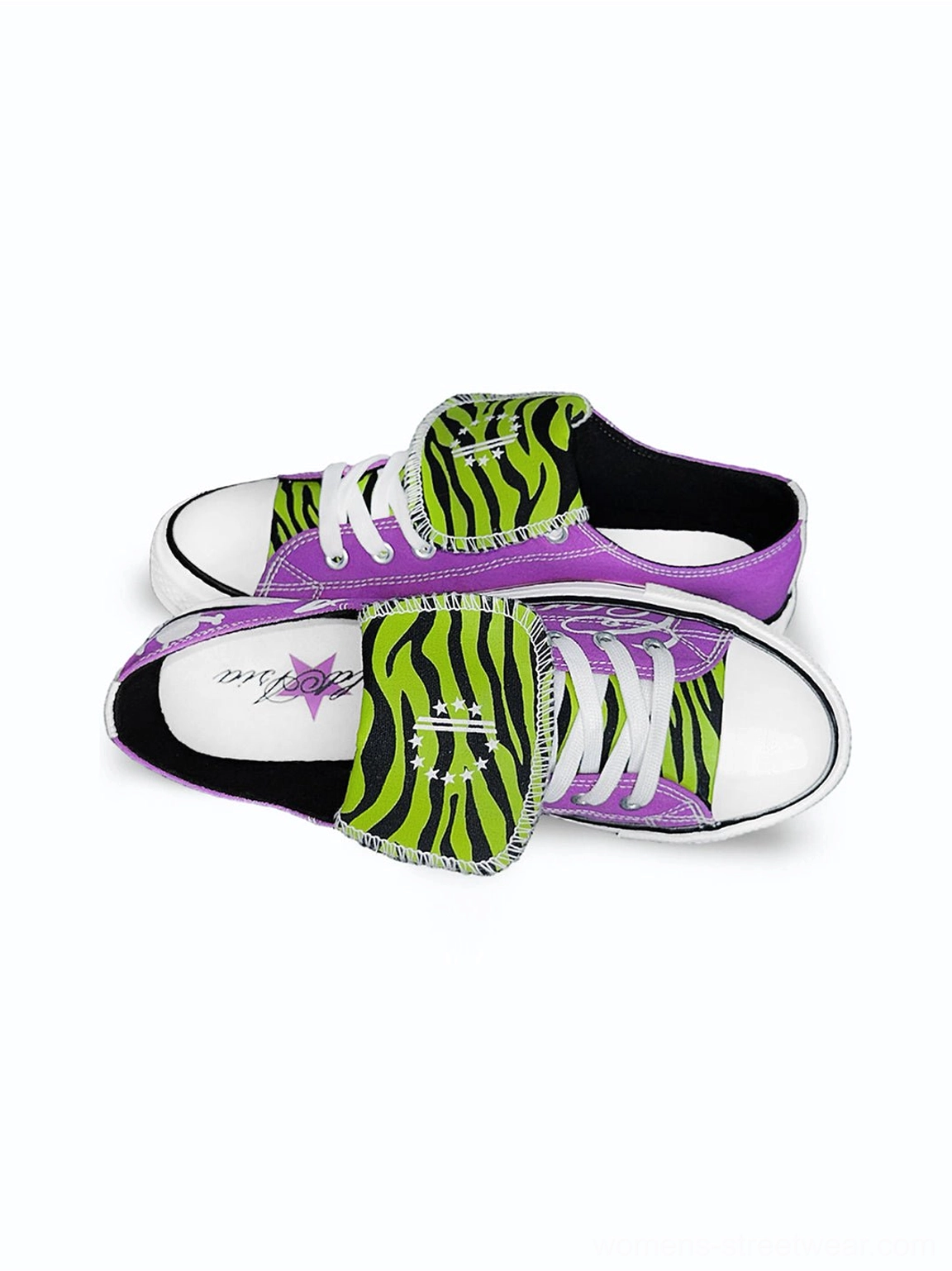 Top down flat lay of purple graphic canvas sneakers with green black zebra print tongues, white rubber soles, white toe caps, and detailed insoles