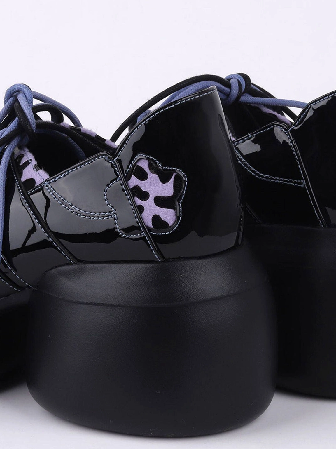 Black patent platform Oxford shoe heel close-up showing butterfly motif, purple trim, and oversized sole