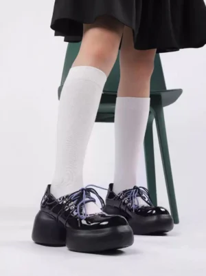 Model wearing glossy black purple leopard platform Oxford shoes with white knee-high socks and black mini skirt