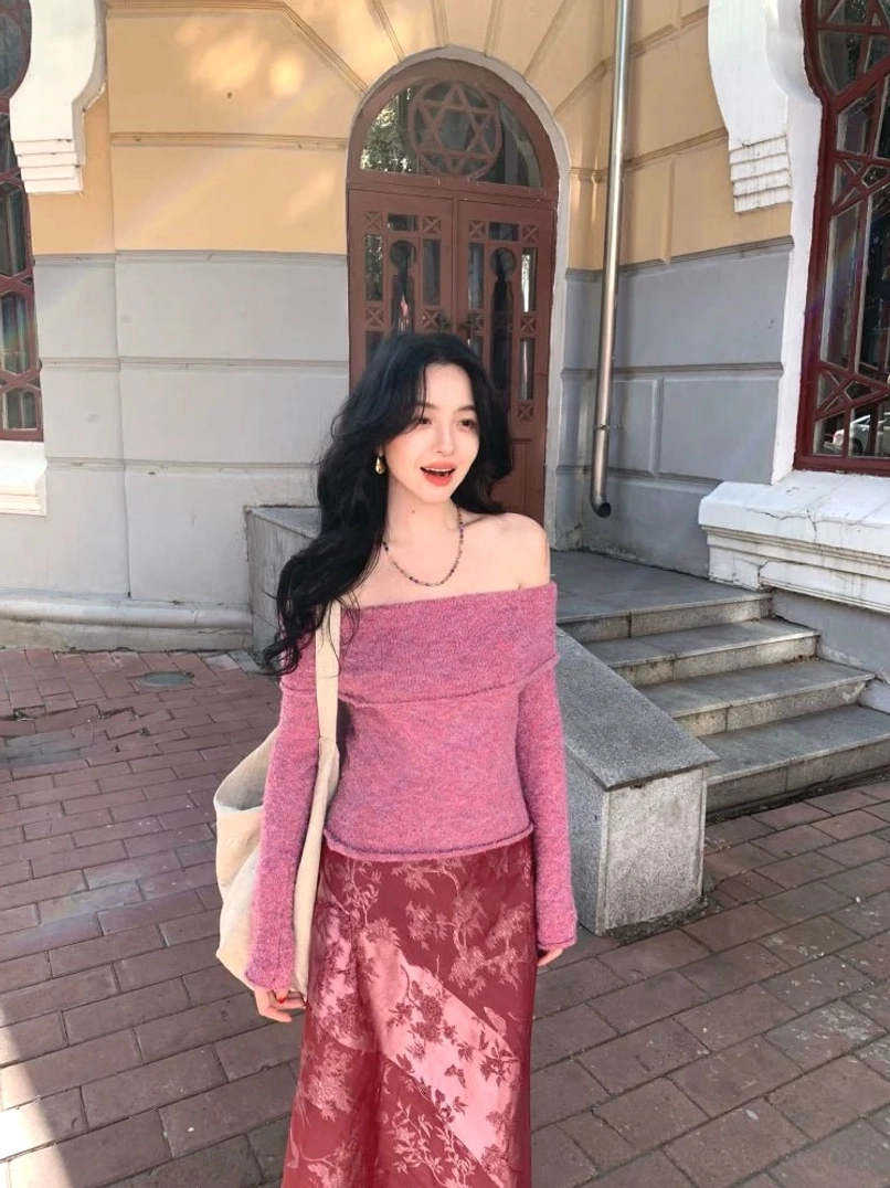 Purple off-shoulder knit sweater top with fold-over neckline and long sleeves styled in a feminine streetwear outfit on a European vintage sidewalk