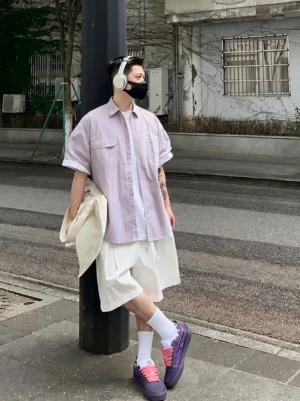 Male model wearing purple platform skate shoes with casual urban streetwear outfit on a city sidewalk