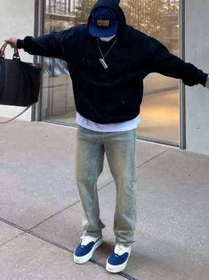 Male model wearing navy blue and off-white quilted platform sneakers with black hoodie and light wash jeans on an urban street
