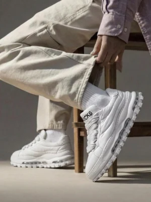 White quilted leather ripple sole trail runner sneakers worn with beige trousers in a casual indoor streetwear outfit