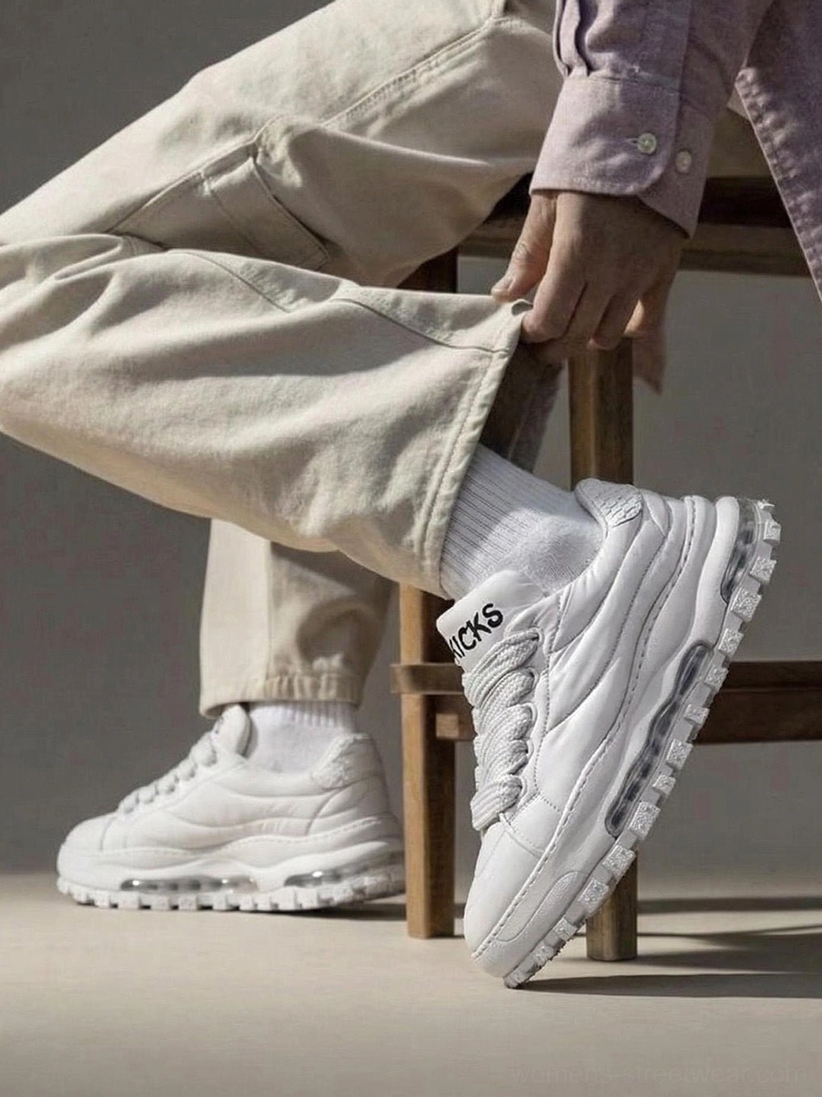 White quilted leather ripple sole trail runner sneakers worn with beige trousers in a casual indoor streetwear outfit