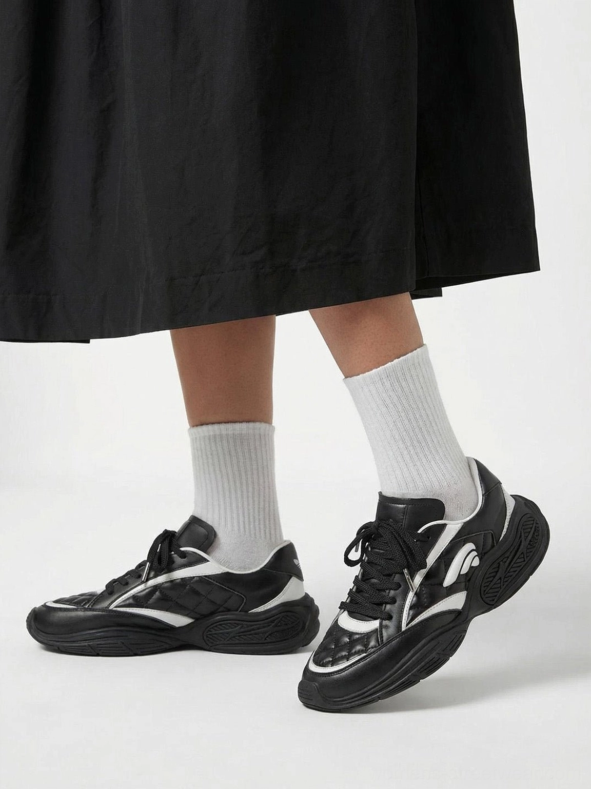 Quilted leather low-profile sneakers styled with a long black midi skirt and white socks for modern streetwear