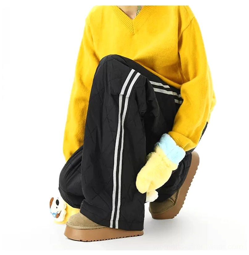 Black quilted wide-leg track pants with white double side stripes in a padded cold-weather streetwear outfit