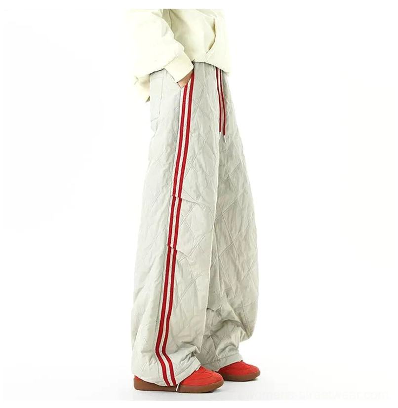 Back side view of gray quilted wide-leg track pants with red athletic stripes and relaxed winter streetwear styling