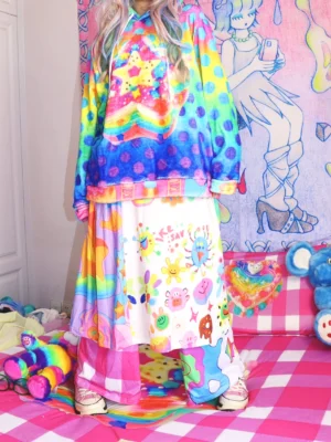 Rainbow doodle print kawaii midi skirt with elastic waist, colorful cartoon graphics, and contrast panels styled in a playful Harajuku streetwear outfit