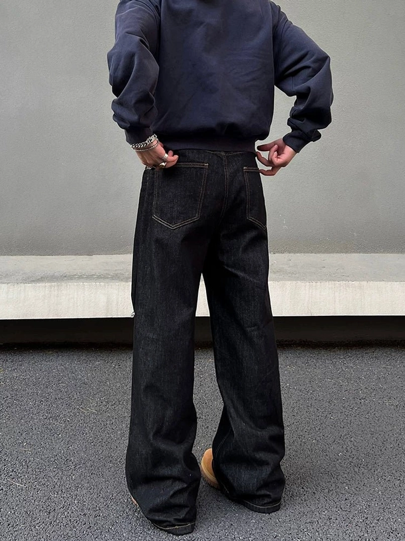 Rear view of dark indigo wide-leg streetwear jeans showing the classic back patch pockets, full-length drape, and relaxed denim silhouette