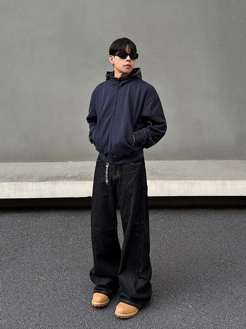 Complete Korean-inspired streetwear outfit featuring dark indigo wide-leg jeans, navy hoodie, black sunglasses, and tan casual work boots