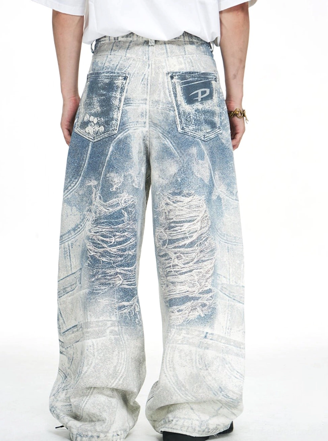 Rear view of blue acid-wash wide-leg baggy jeans with two back pockets, pale distressed fading, and an oversized stacked hem