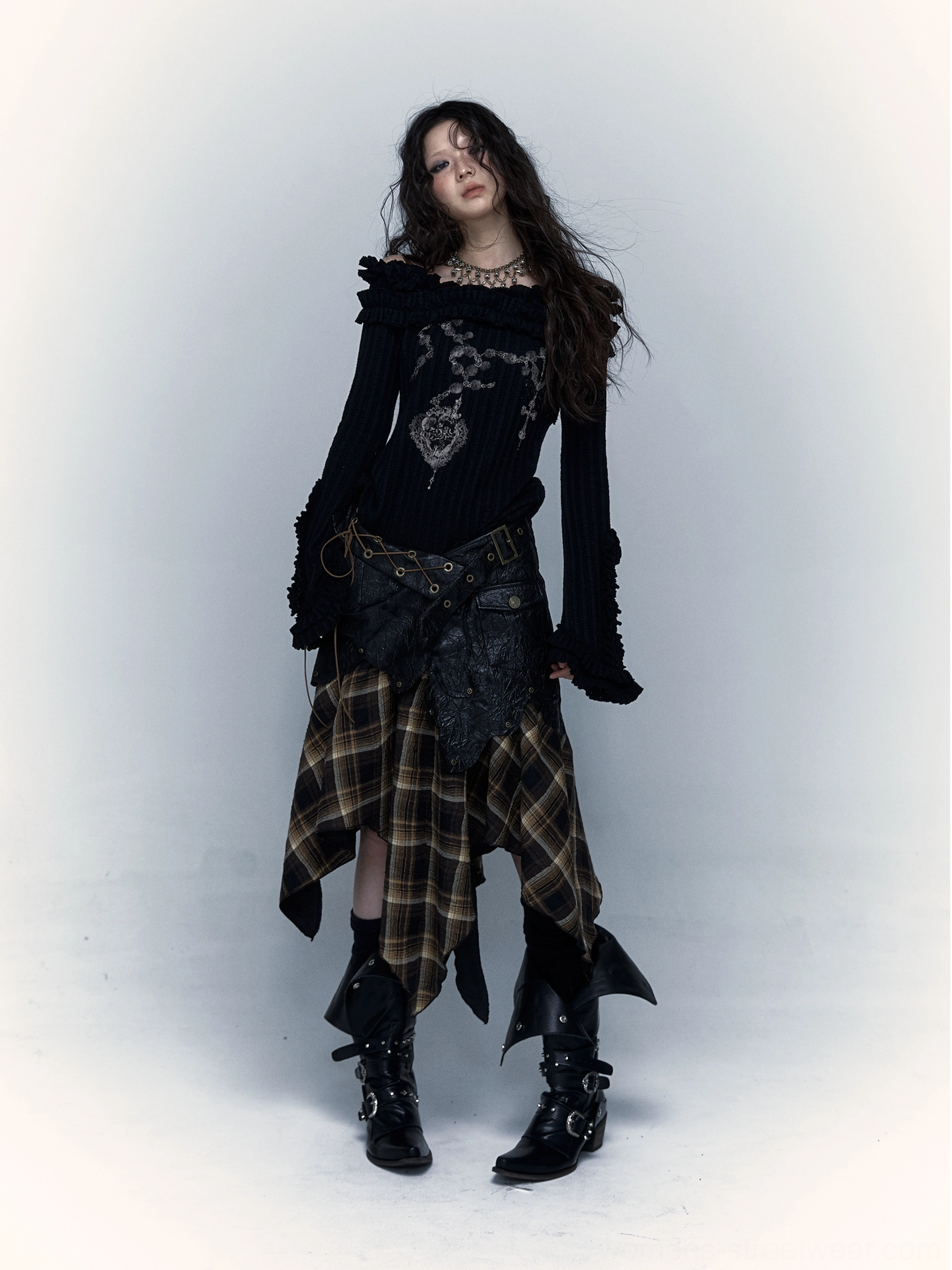 Full front view of women’s brown plaid asymmetrical handkerchief hem skirt styled with an off shoulder knit top and biker boots
