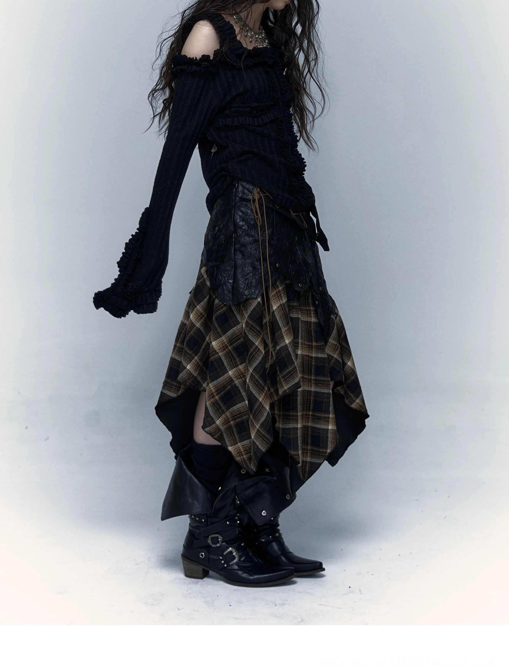 Full side view of brown tartan asymmetrical handkerchief hem midi skirt styled with an off shoulder ribbed knit top and biker boots