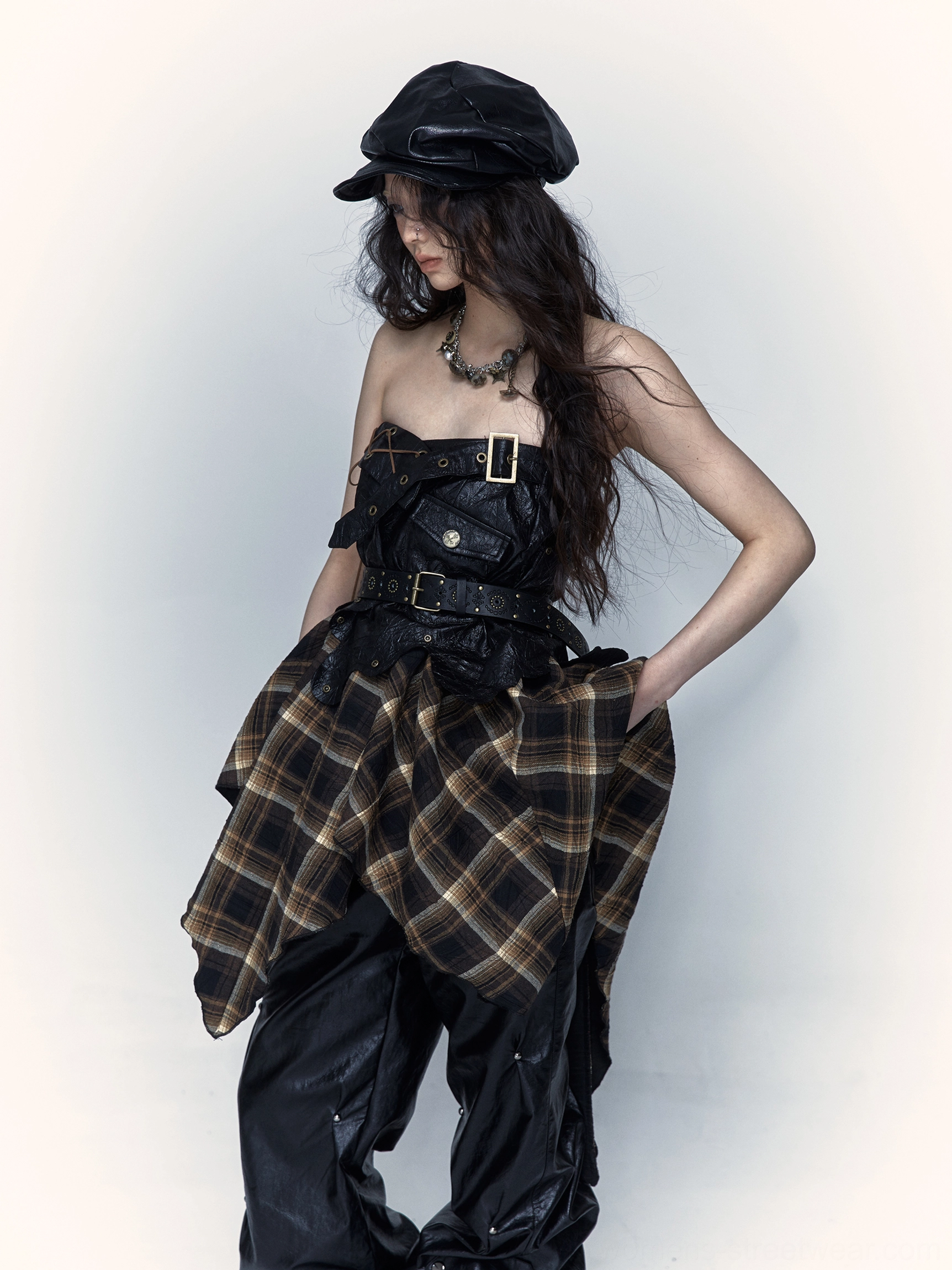 Women wearing brown black and yellow tartan asymmetrical punk midi skirt with buckled faux leather waist panel in side front studio view
