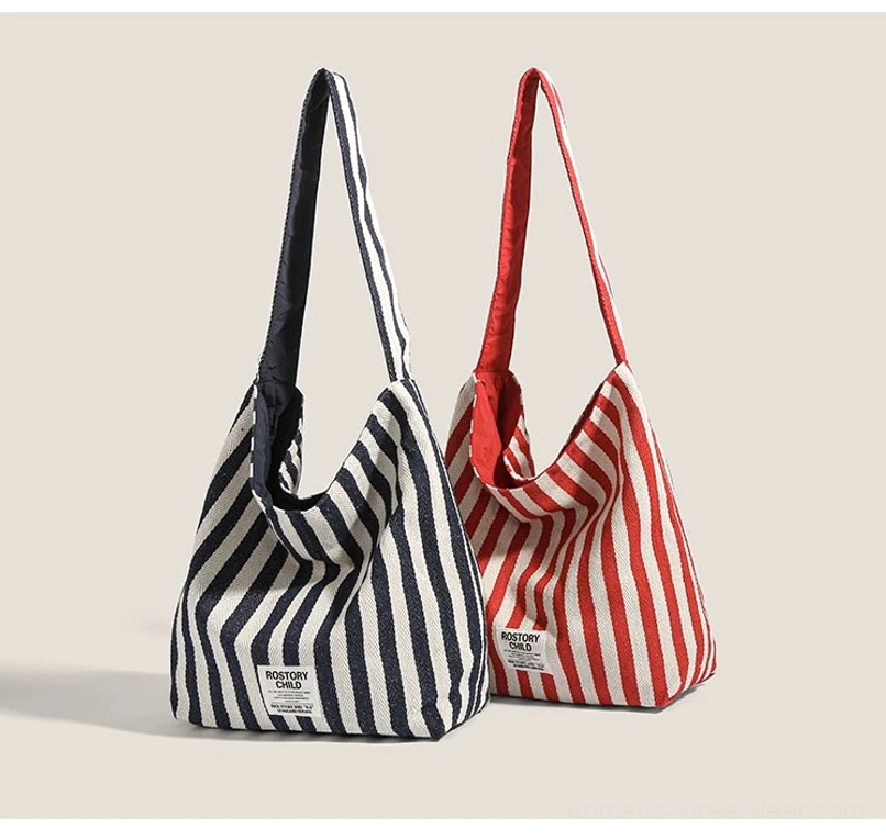 Red and navy blue candy stripe canvas hobo bags shown together with wide shoulder straps and slouchy silhouettes