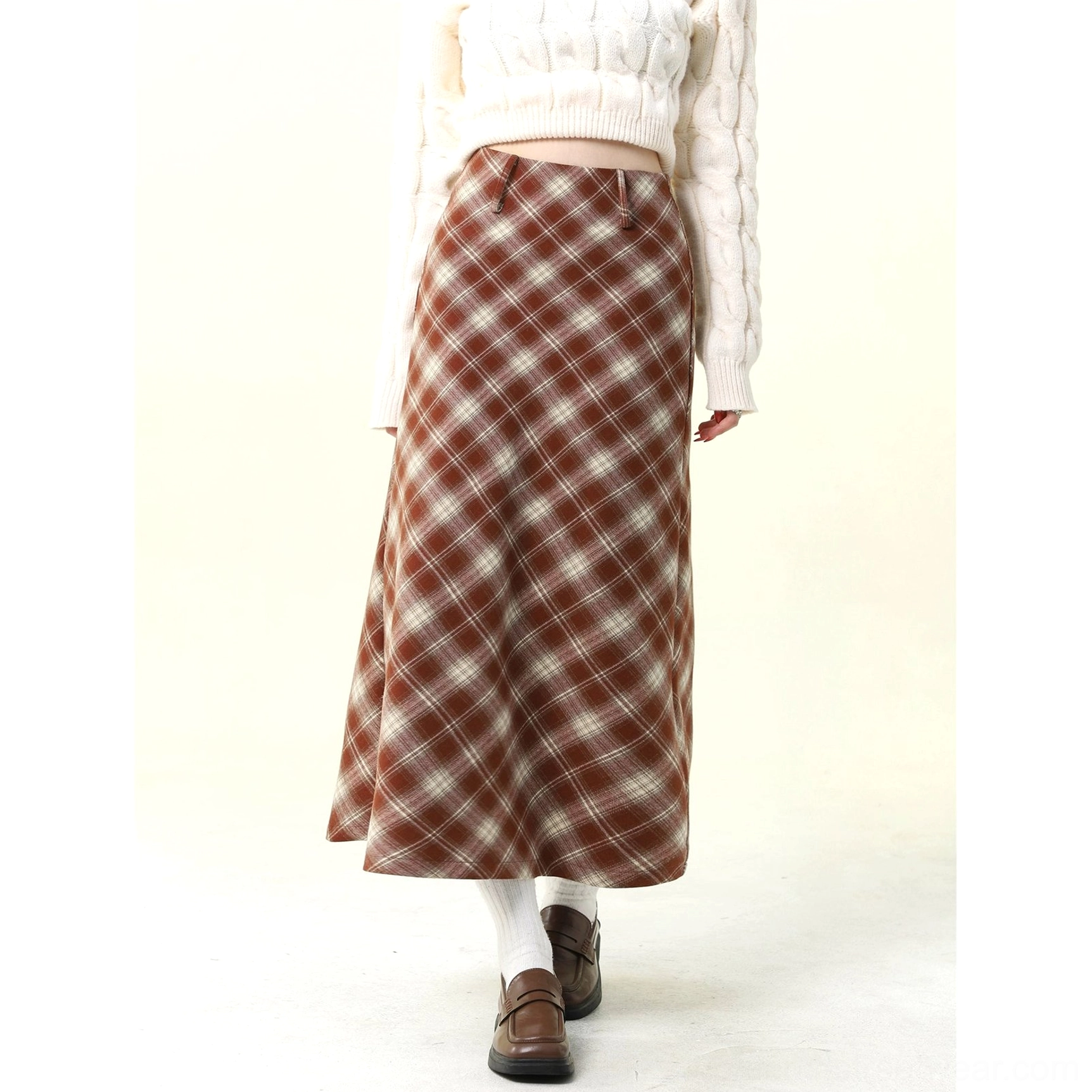 Full-body side-front view of a red and brown plaid high-waisted wool skirt with a white cropped sweater and leather loafers