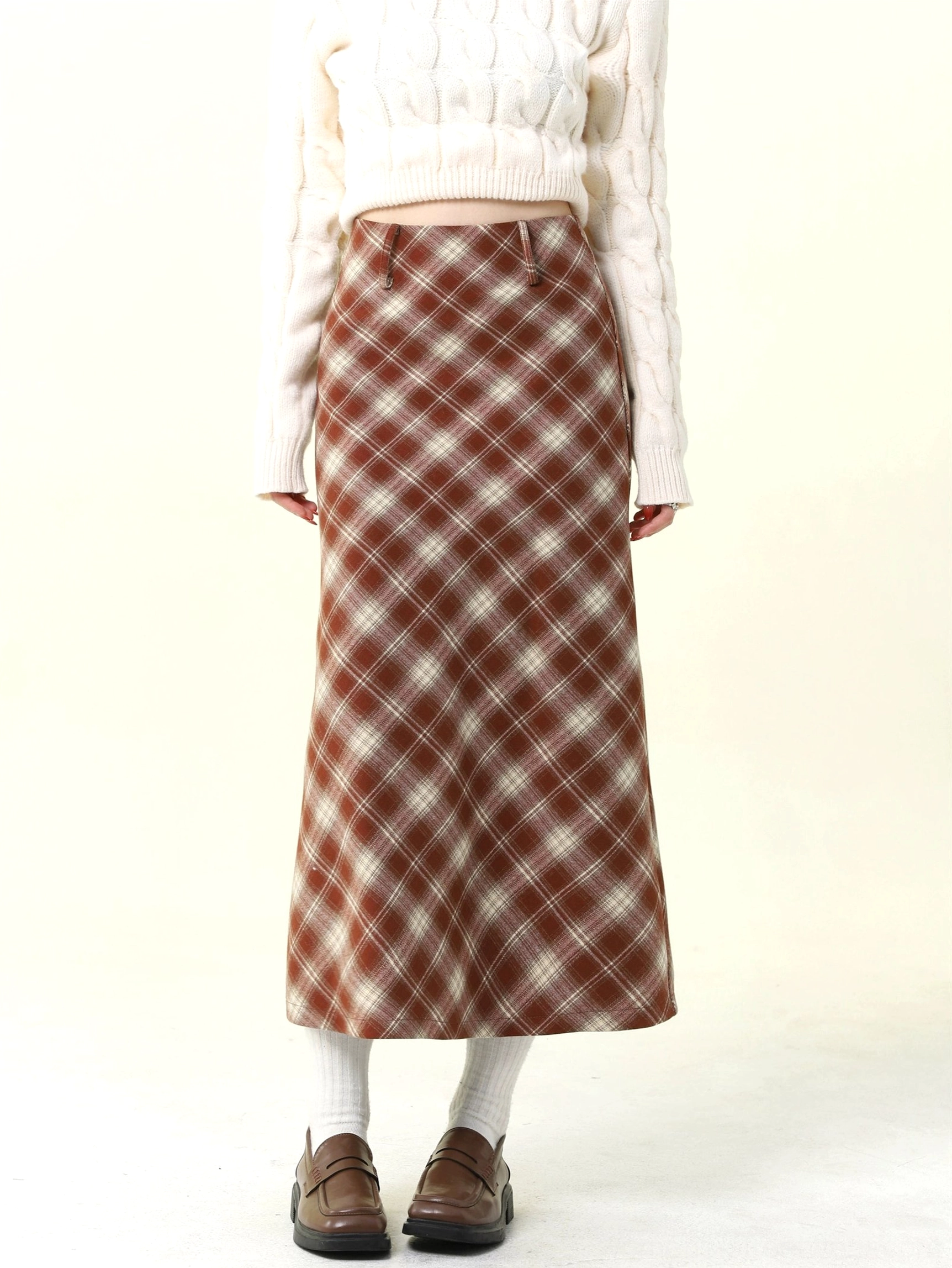 Back-side view of a flowing A-line red and brown tartan plaid wool skirt styled with a cropped white sweater and leather loafers
