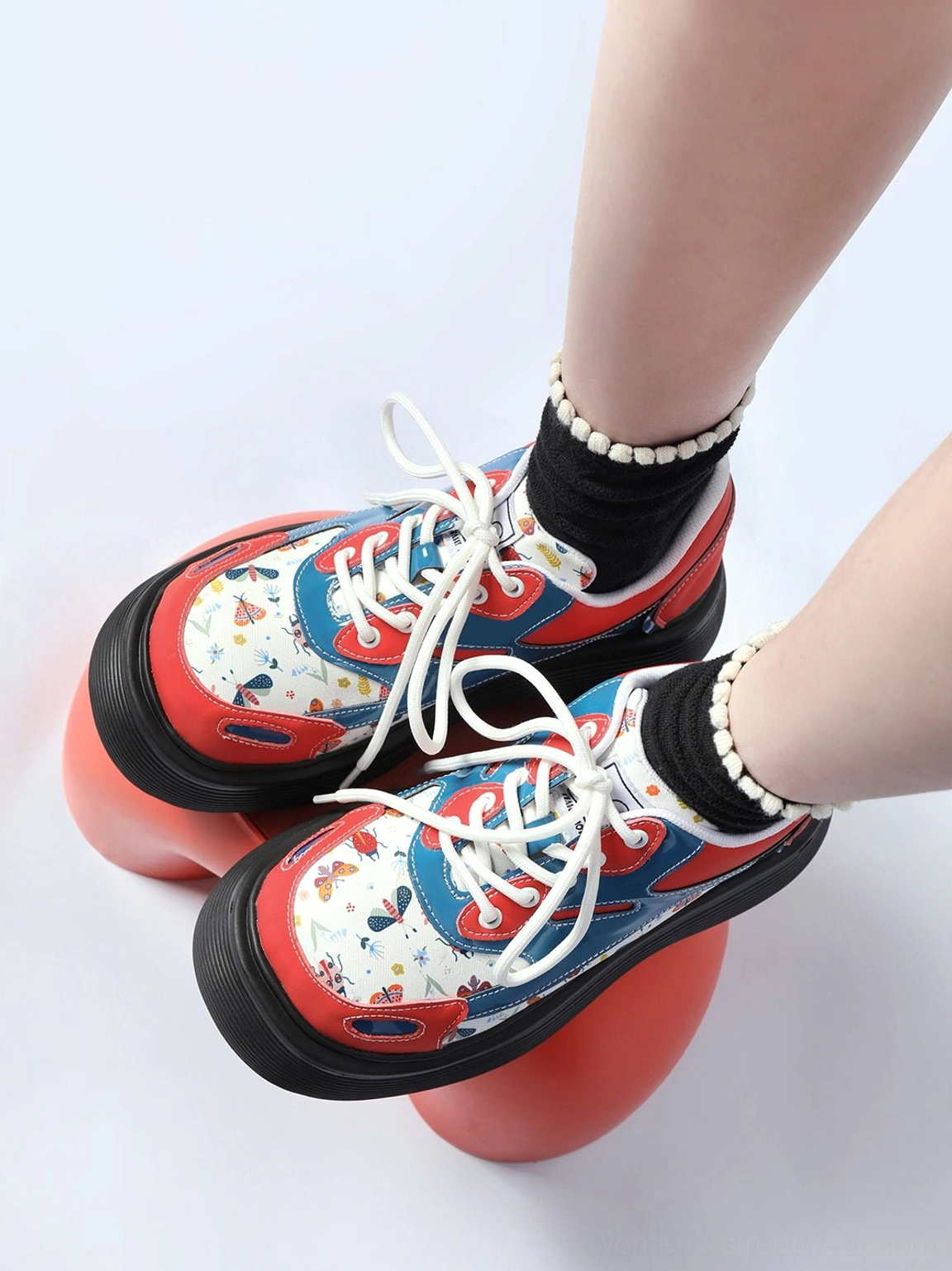 Close-up side view of red butterfly platform derby shoes showing the chunky black sole and printed upper