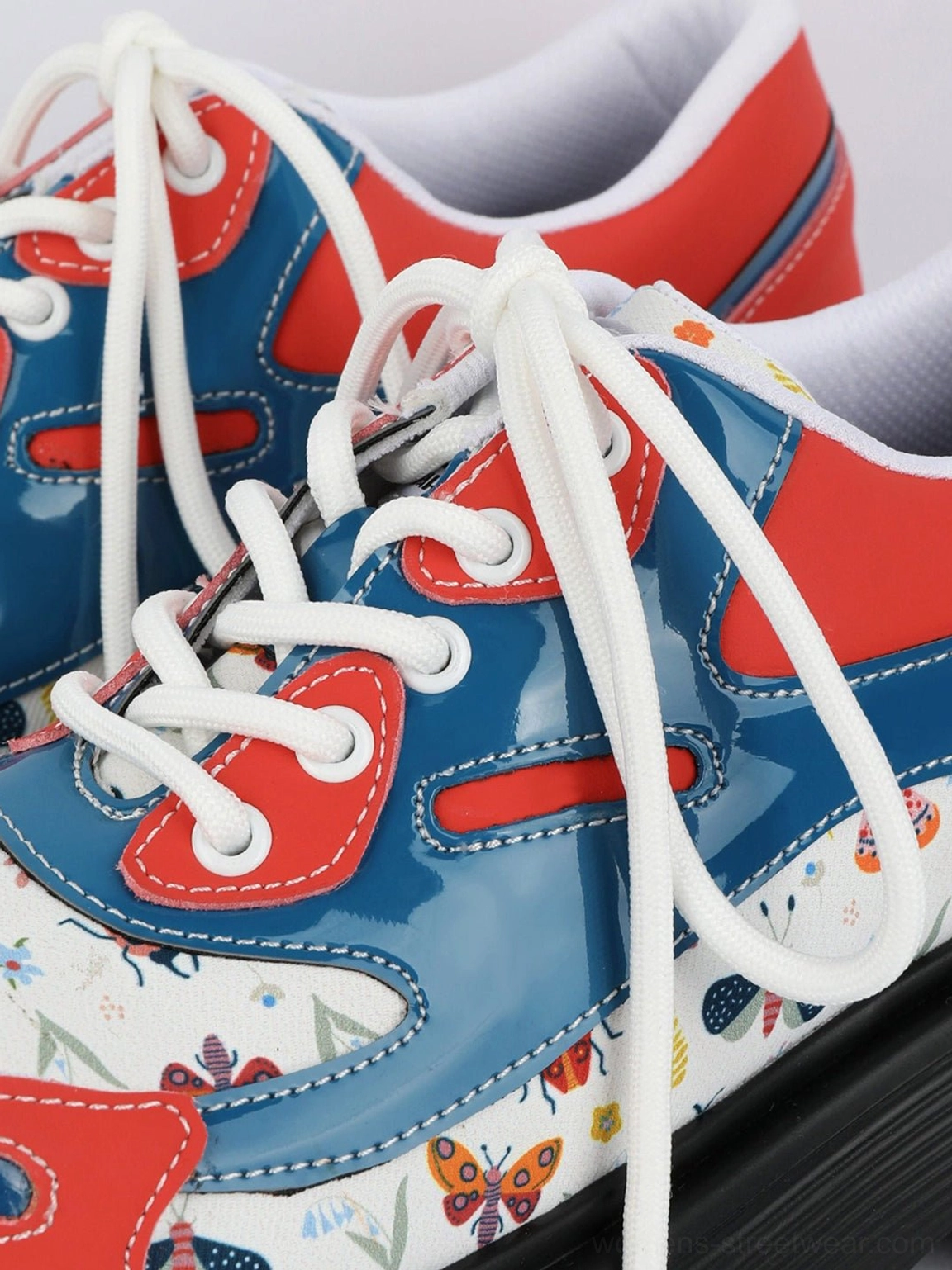 Overhead close-up of red butterfly print platform derby shoe pair with blue panels and white laces