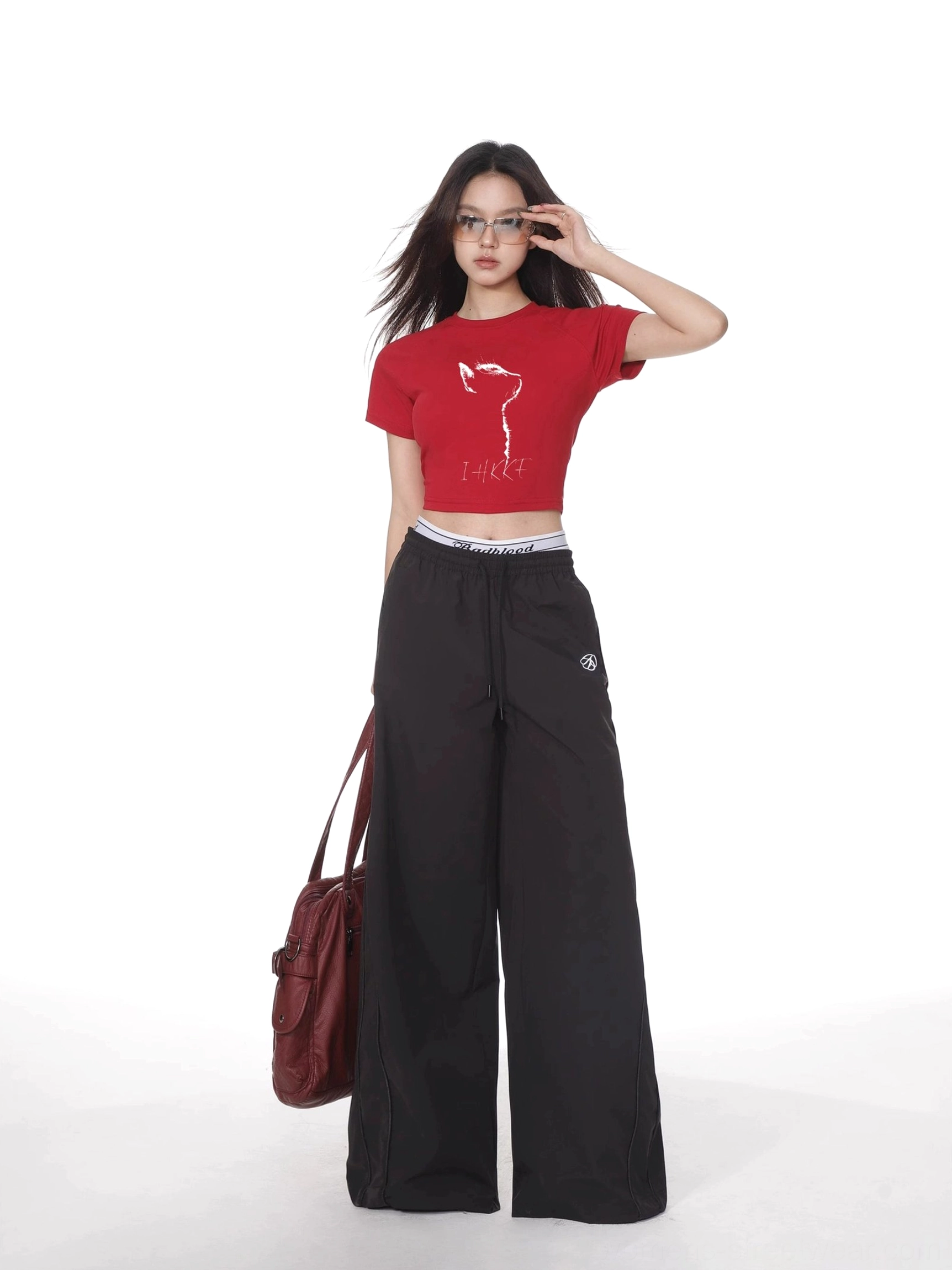 Bright red cat graphic cropped fitted short sleeve t-shirt styled with black wide leg trousers and burgundy shoulder bag