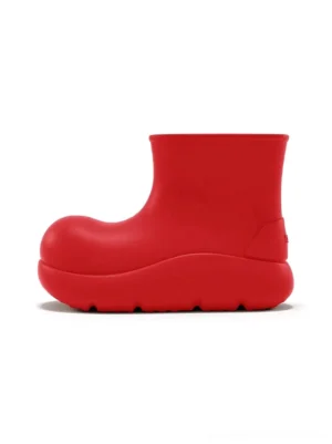 Left side profile of bright red chunky short rain boots with matte finish, rounded toe, thick platform sole, ankle-height streetwear silhouette, and small heel logo