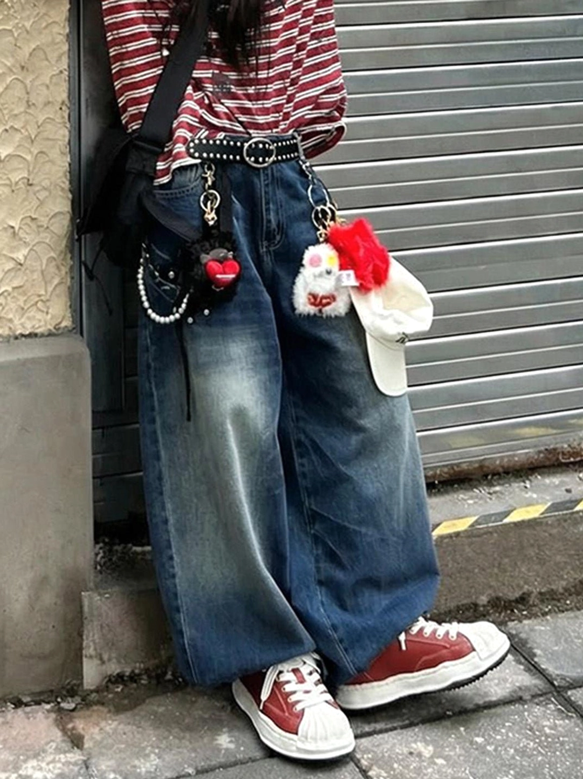 Red court sneakers paired with wide-leg blue jeans, pendant details, and a crossbody bag for a retro Y2K outfit