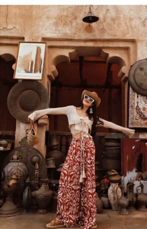 Red and white retro floral wide-leg pants styled with a cropped knit top in front of a vintage antique shop doorway