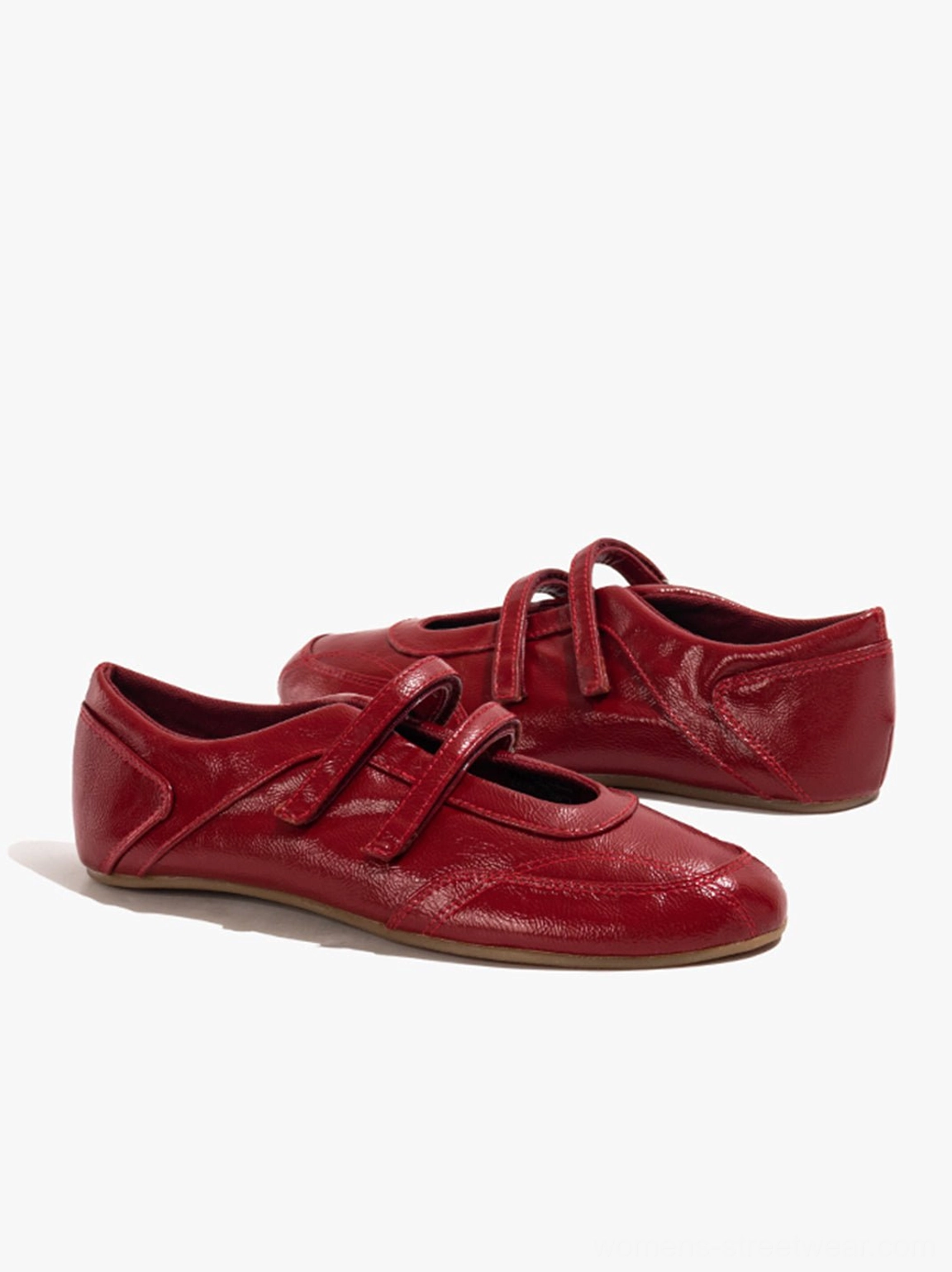 Three-quarter view of red crisscross strap flats showing rounded toe, heel, and low flat profile