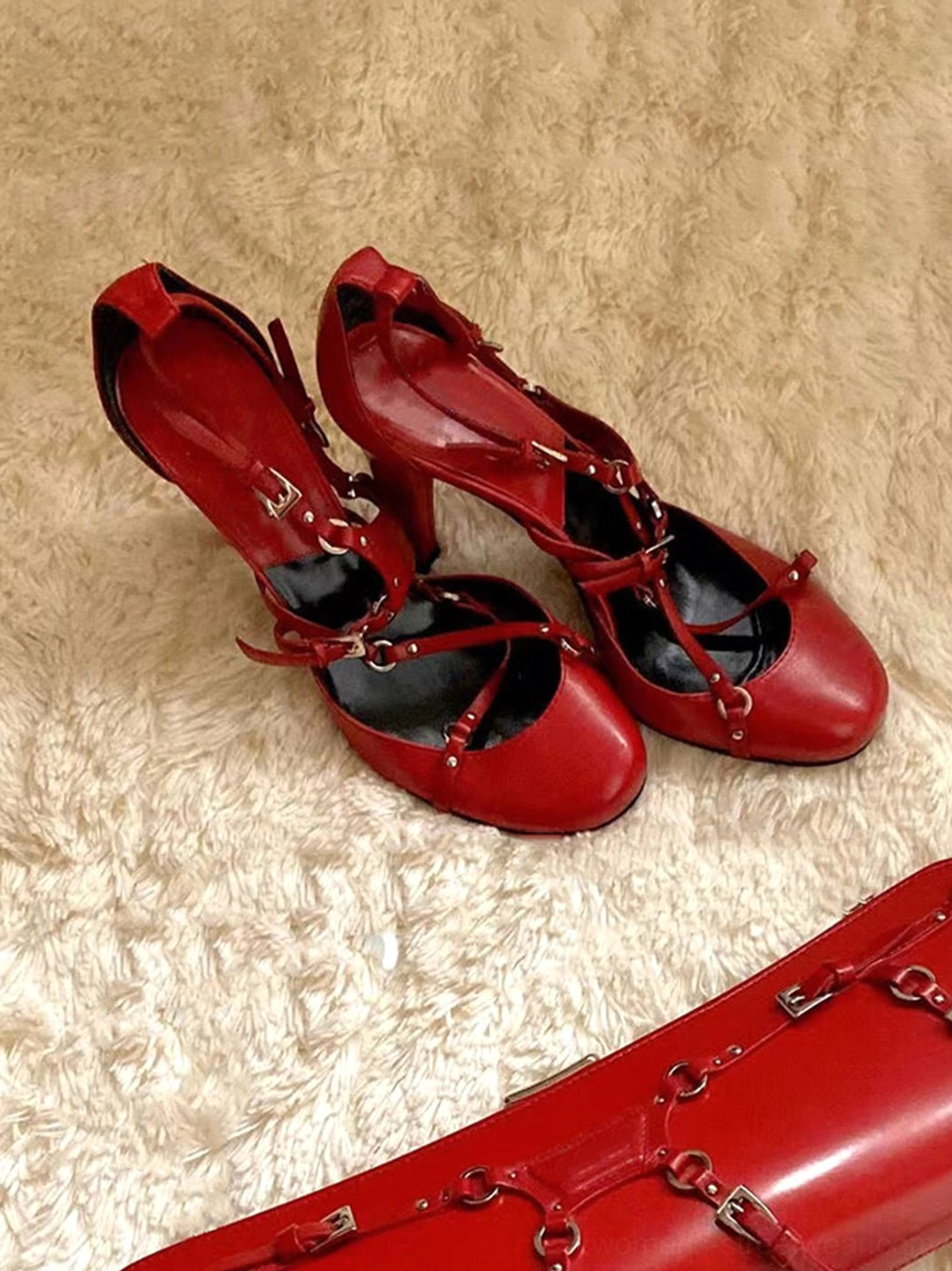 Red cross-strap round-toe pumps featuring a 9 cm block heel, silver-tone hardware, and a matching red handbag in a low-angle view