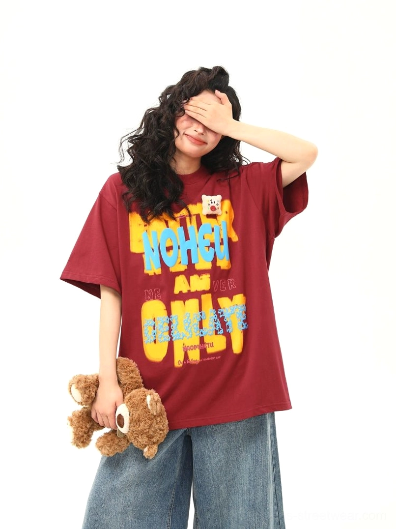 Red drop shoulder oversized streetwear tee featuring colorful graffiti text graphics and a small teddy bear chest patch