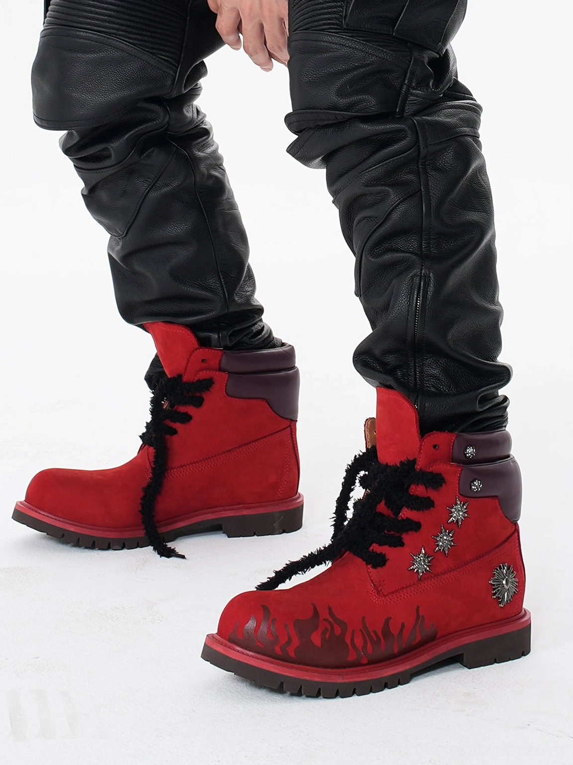 Model wearing red flame appliqué genuine leather combat boots with black leather cargo pants in urban streetwear styling