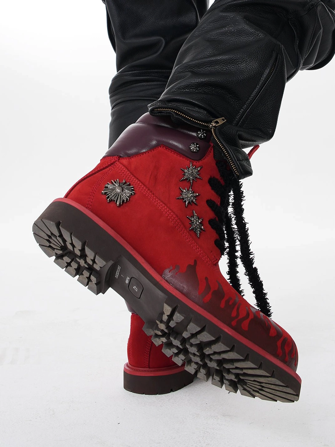 Overhead side view of red flame appliqué genuine leather combat boots showing deep lug tread, black laces, and metal details