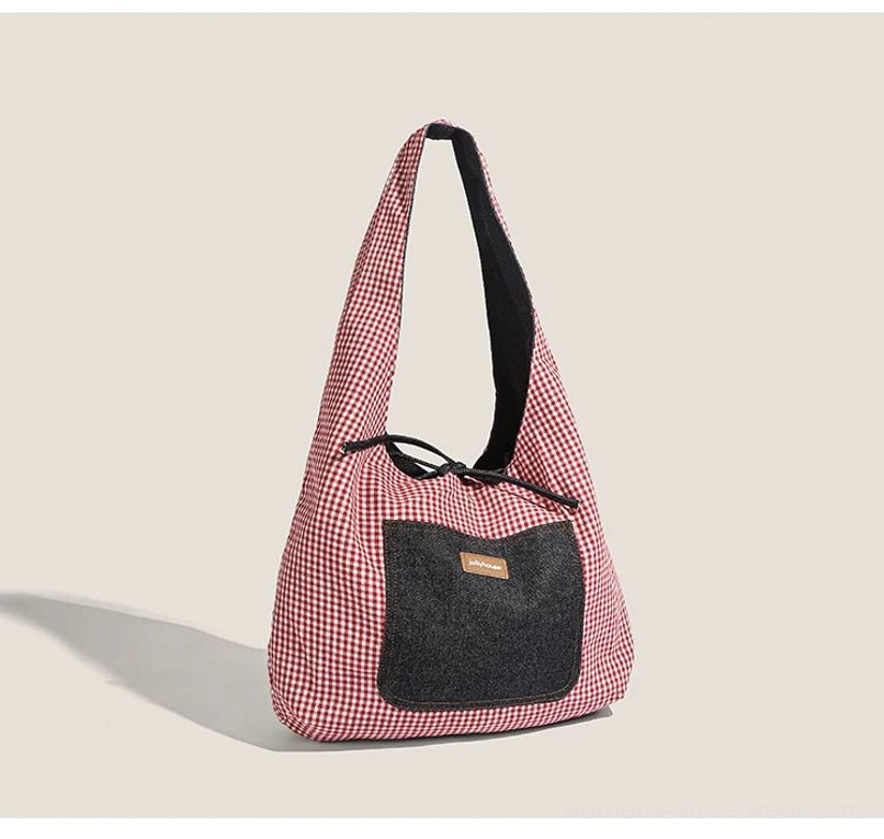 Red gingham side of denim sling tote with black denim front pocket, black shoulder strap, and drawstring top