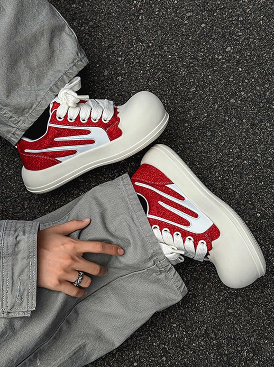 Red glitter chunky platform sneakers worn with gray denim pants on asphalt in a Y2K Seoul streetwear outfit