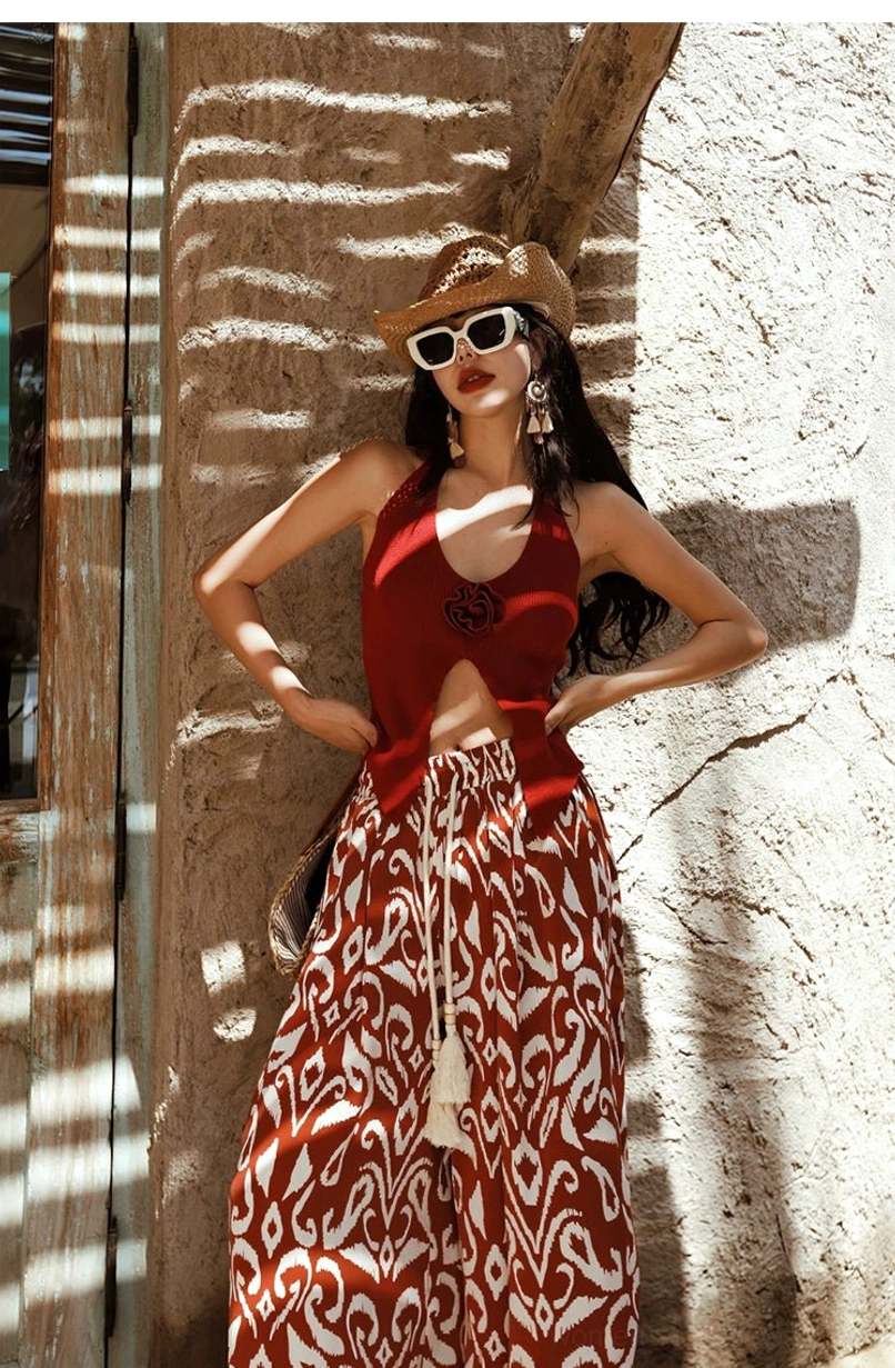 Red halter neck knit rose top with dimensional floral appliqué and split pointed hem styled with printed wide leg pants