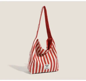 Red and off-white candy stripe canvas hobo shoulder bag with wide strap and relaxed Seoul streetwear silhouette front view