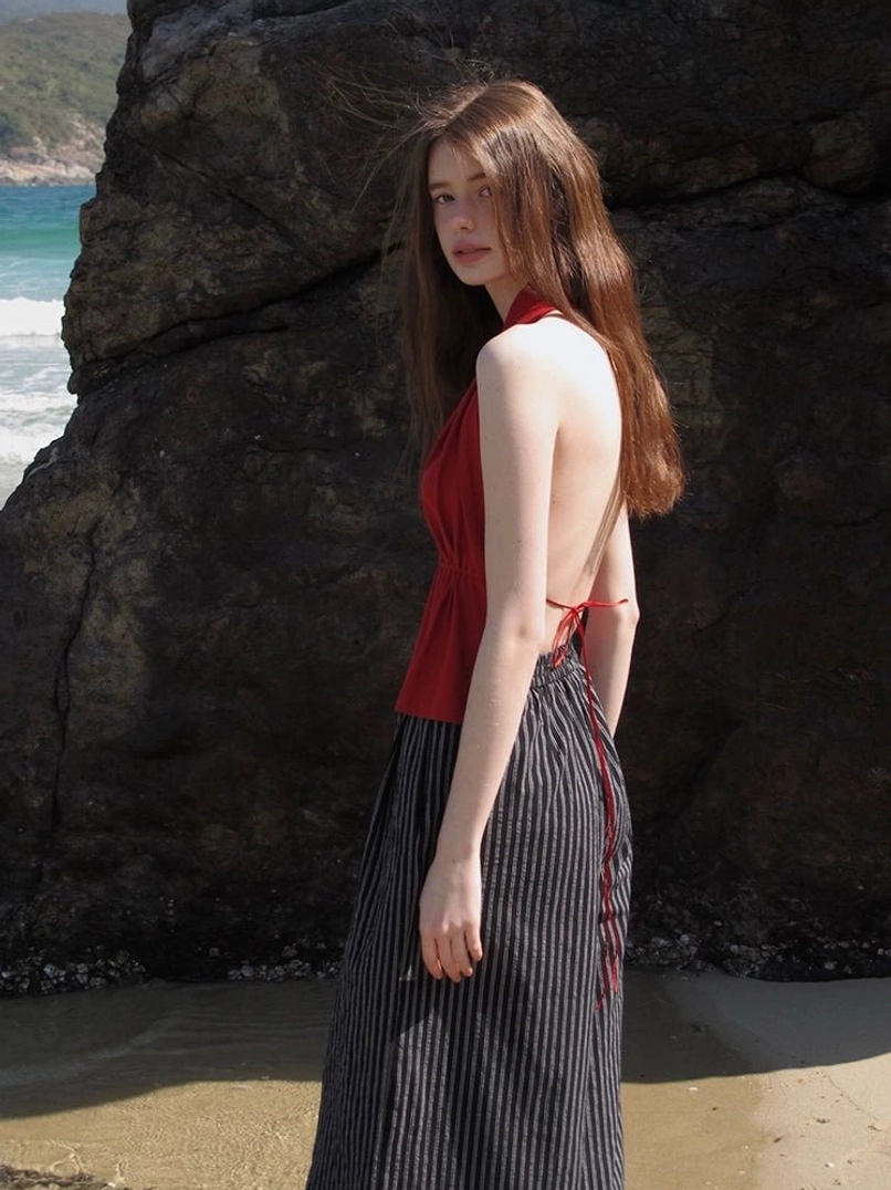 Red open-back halter peplum top with adjustable waist ties styled with a long striped skirt