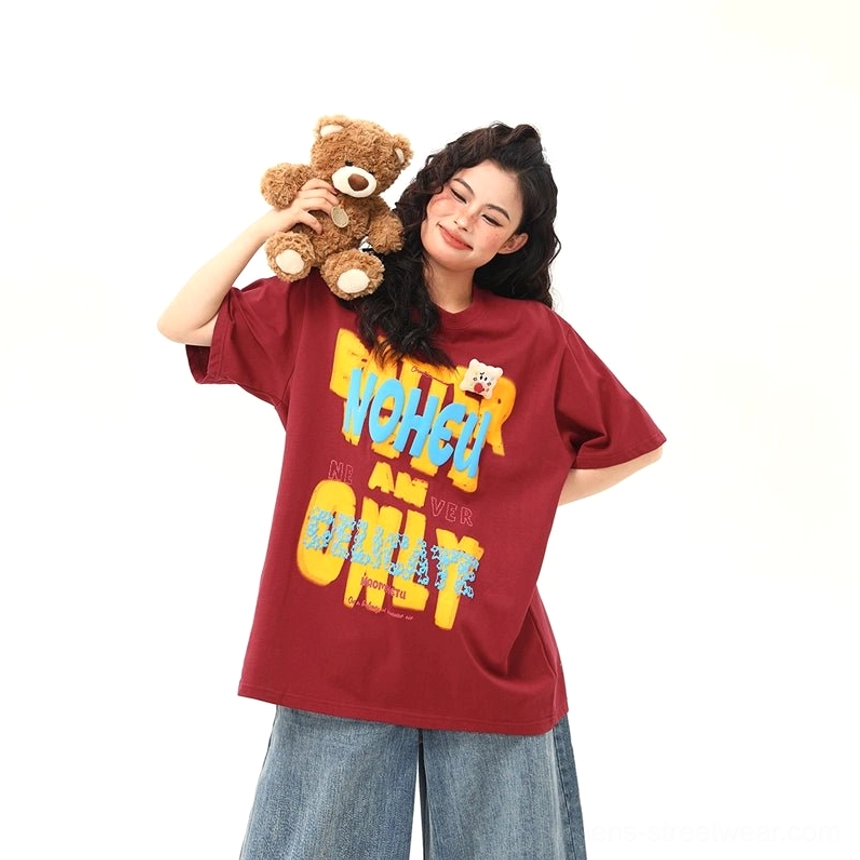 Red oversized graphic streetwear T-shirt with colorful retro lettering and teddy bear chest patch styled with denim