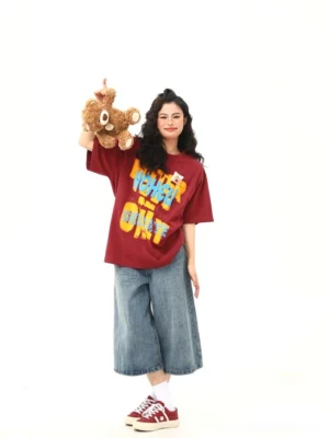 Red oversized graphic T-shirt styled with wide-leg blue jeans and red canvas sneakers in a Korean streetwear outfit